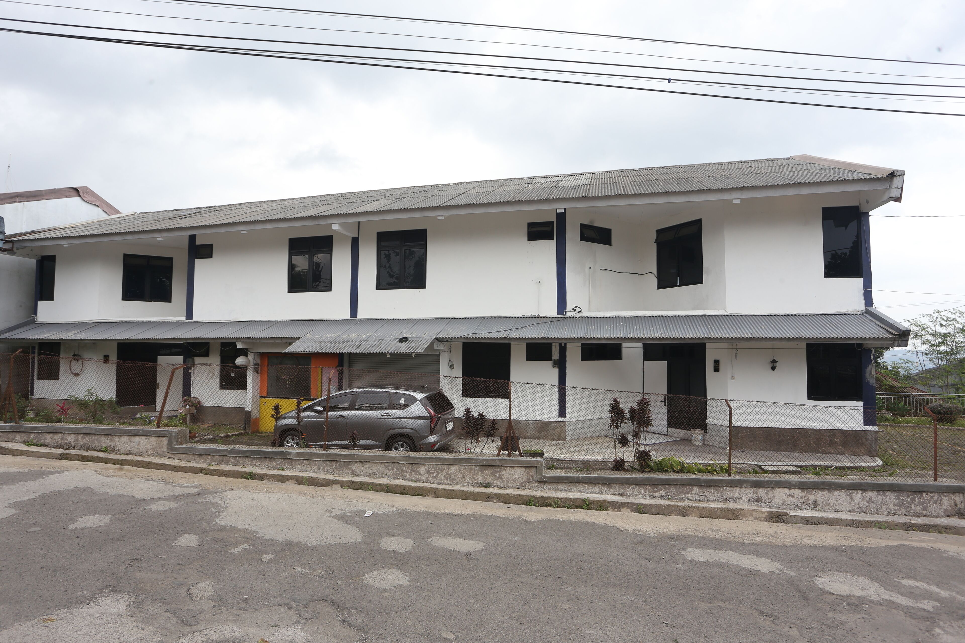 A two-story building with a grey roof and white walls.