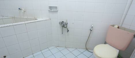 A small, tiled bathroom with a toilet, a shower, and a sink.