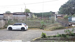 A white SUV parked on a paved area with a garden and a building in the background. - Villa Agape Near Puncak By ARBA (Cipanas)