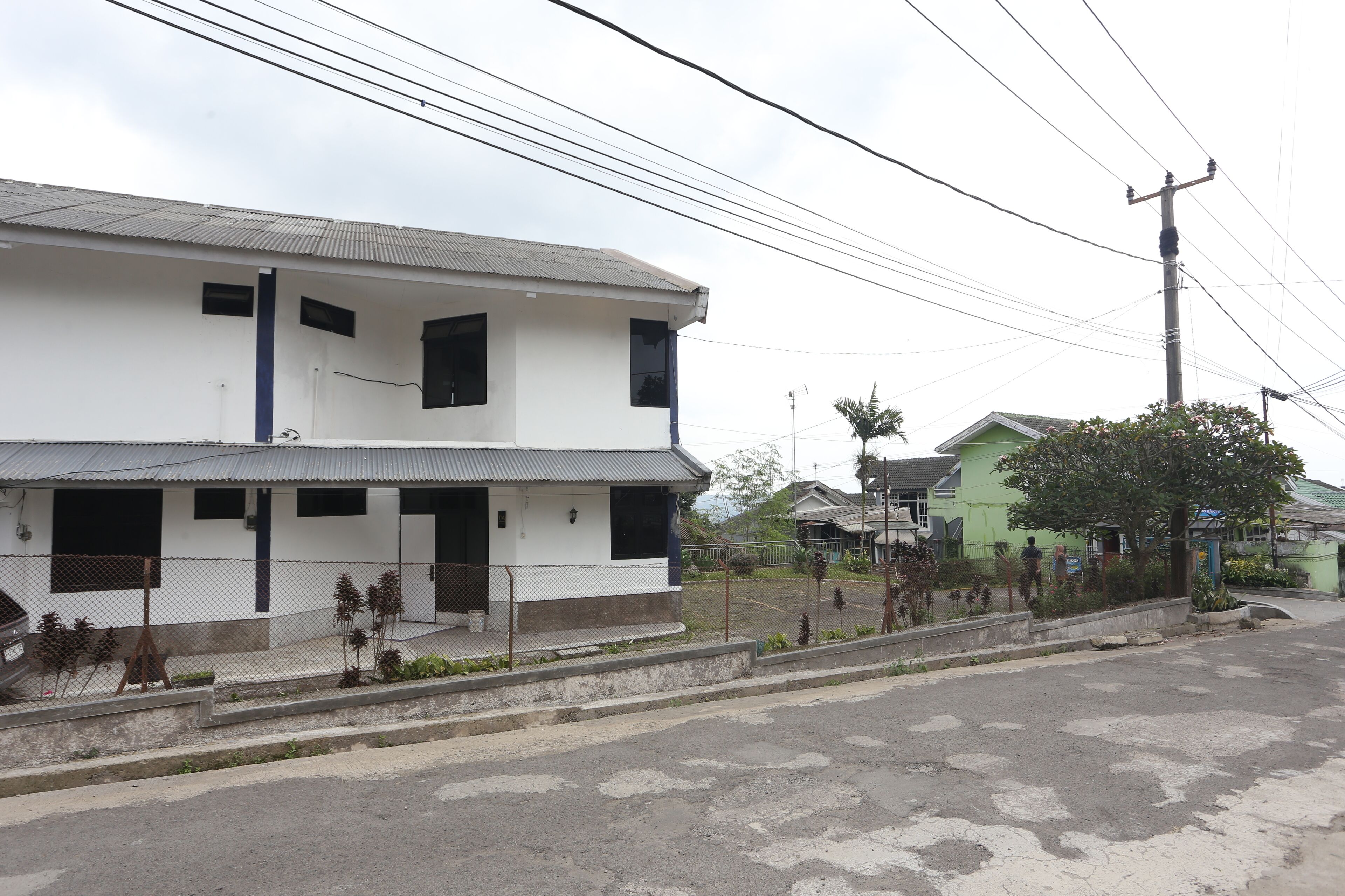 Un bâtiment à deux étages, doté d’un toit plat et d’une cour avant clôturée.