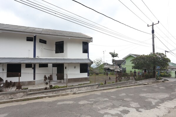 A two-story building with a flat roof and a fenced front yard. - Villa Agape Near Puncak By ARBA (Cipanas)