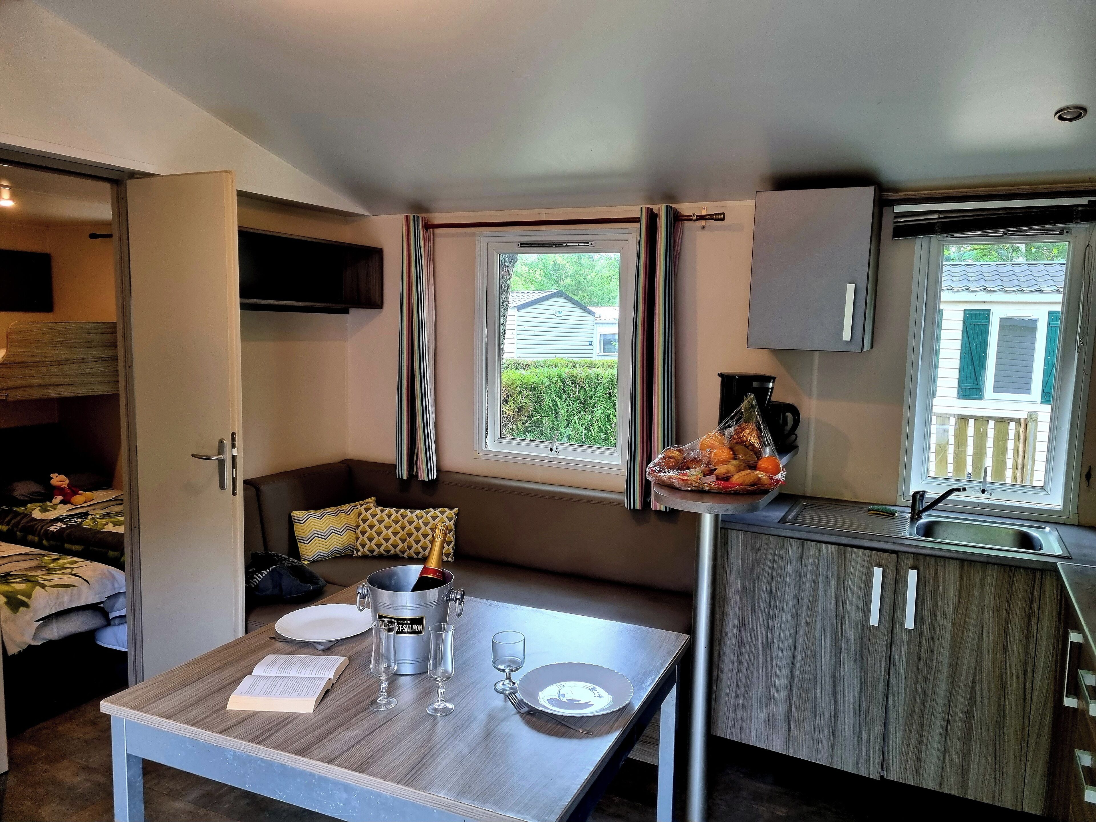 Ein kleines Zimmer mit einer Küchenzeile, einem Essbereich und einem Fenster mit Blick auf Grünflächen.