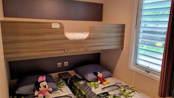 Ein Etagenbett mit Holz-Kopfteil, zwei Kissen und einem Mickey Mouse Kuscheltier auf der unteren Liegefläche.