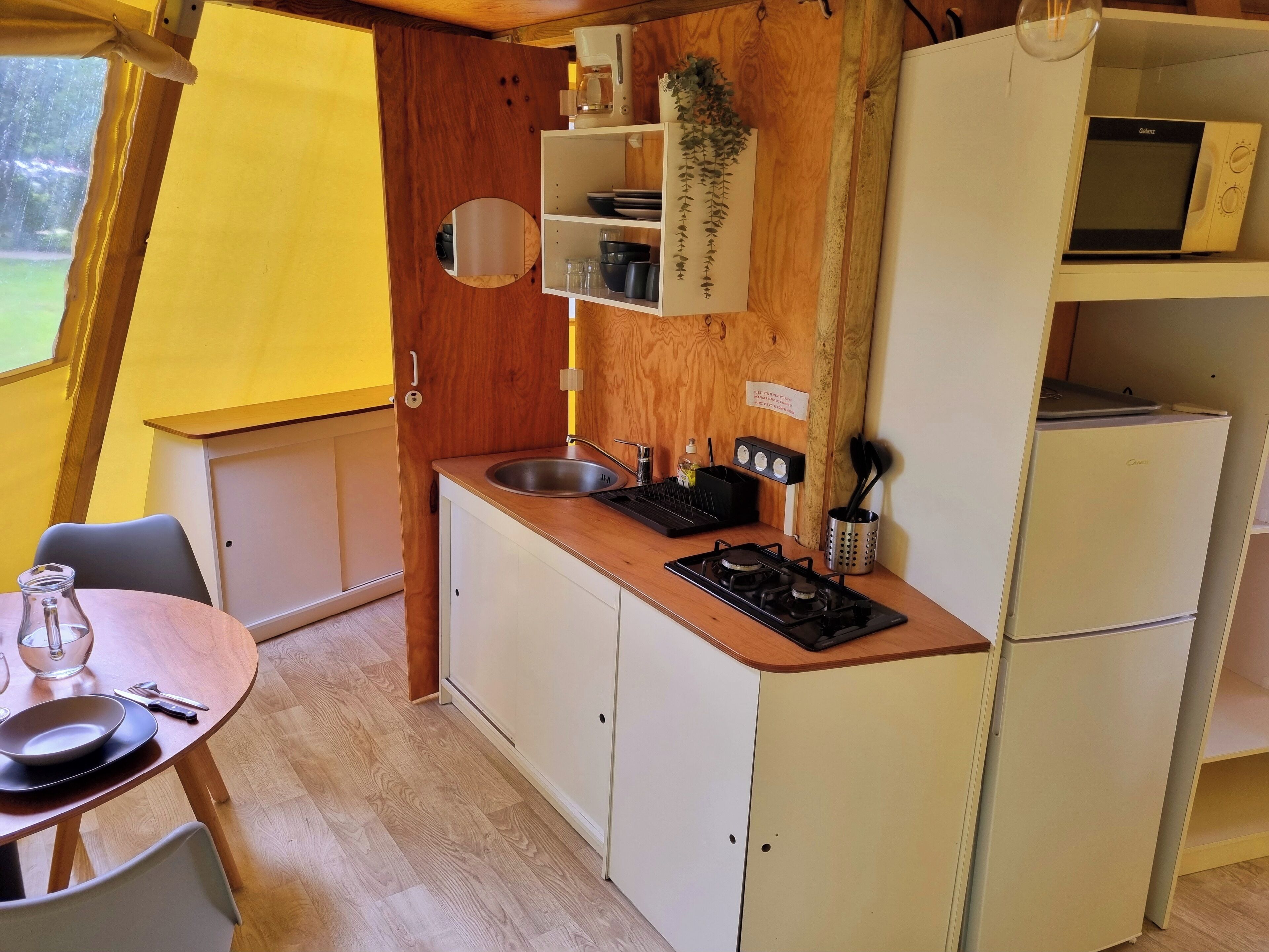 Una cocina compacta con un lavamanos, estufa y microondas.