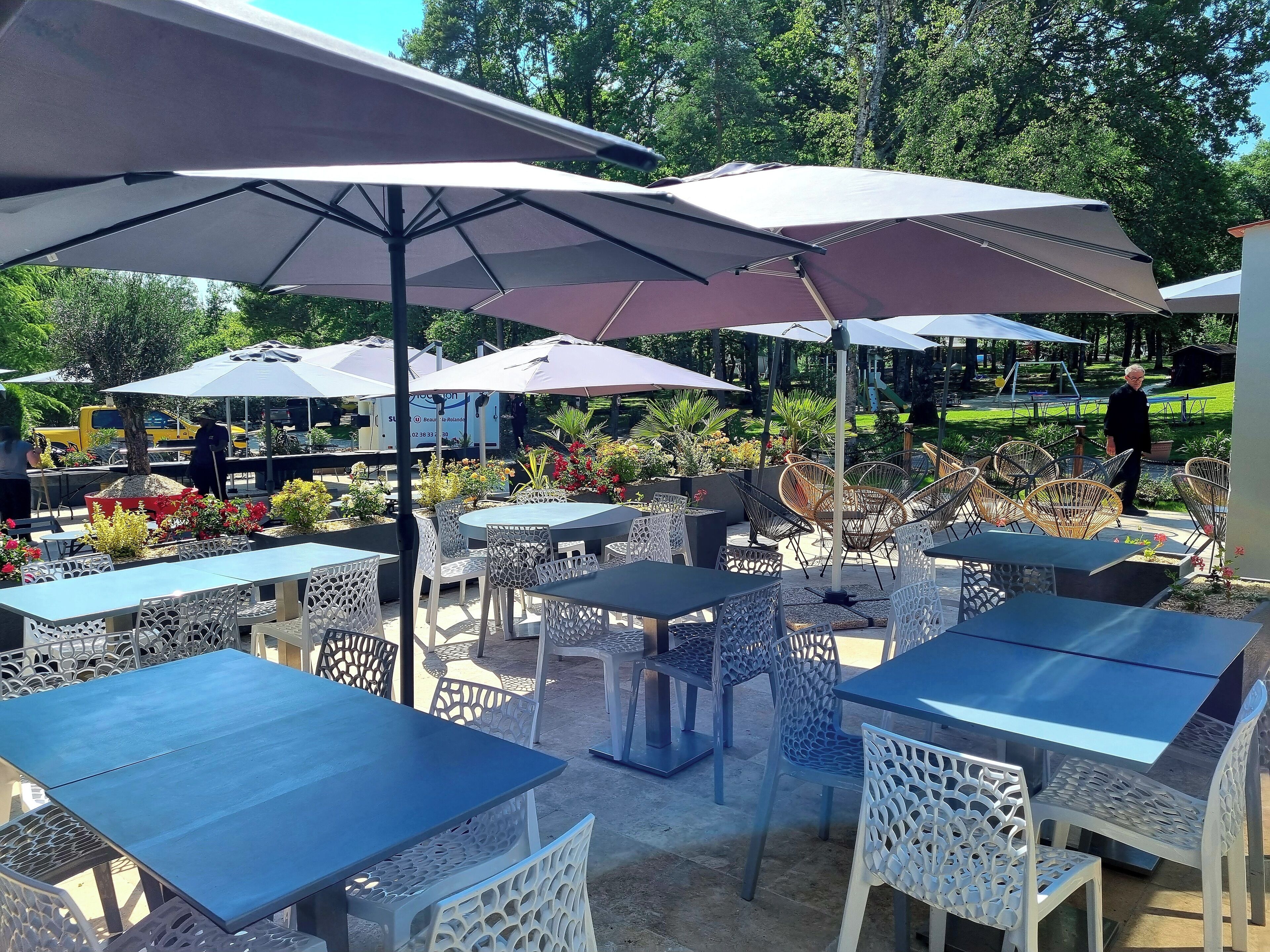 Outdoor seating with tables and chairs, umbrellas, and a garden area.