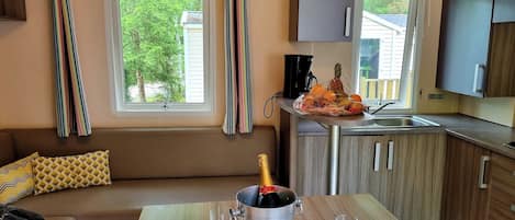 A cozy kitchenette with a dining area, a coffee maker, and a bottle of champagne.