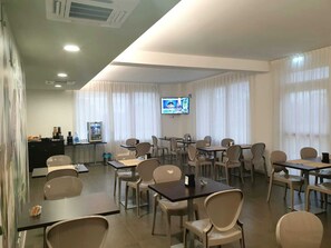 A conference room with tables and chairs, a television screen, and a refrigerator. - Hotel Grel - Modern Comfort with a View of the Iblei Mountains x4 (Chiaramonte Gulfi)