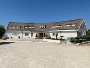 A two-story building with a sloped roof, a covered entrance, and a sign reading "HOTEL GREL". - Hotel Grel - Modern Comfort with a View of the Iblei Mountains x4 (Chiaramonte Gulfi)