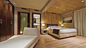 Une chambre d’hôtel moderne avec un grand lit, un plus petit lit, une armoire, un miroir et un tableau au mur.