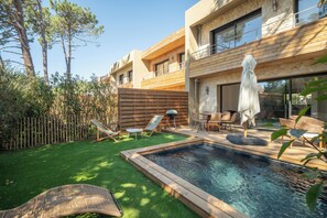 Ein moderner Poolbereich im Freien mit Liegestühlen und einer Holzterrasse.