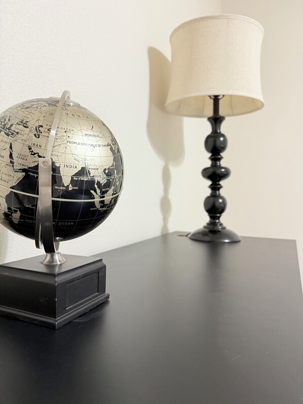 A globe on a black stand next to a lamp on a table. - Oil Patch Getaway (Midland)