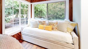 A cozy room with a large window, a sofa with patterned cushions, and a wooden ceiling. - Lucky Clover over the Covered Bridge (Eureka)