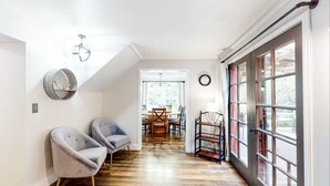 A hallway with two armchairs, a dining area in the background, and a large window with a metal rack. - Lucky Clover over the Covered Bridge (Eureka)