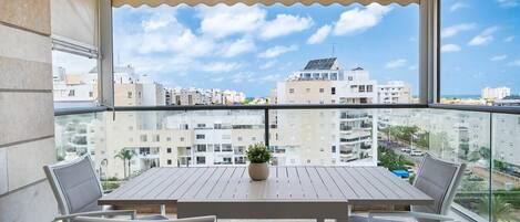 A balcony with a wooden table, two chairs, and a potted plant.