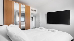 Ett hotellrum med en stor säng, en garderob i trä och en platt-TV.