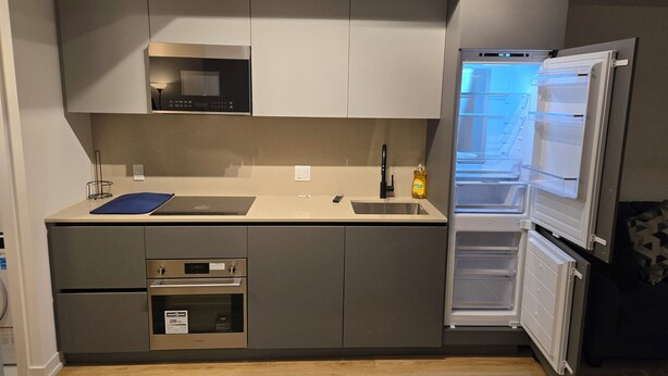 Cocina compacta con horno integrado, microondas y refrigerador con puerta transparente.