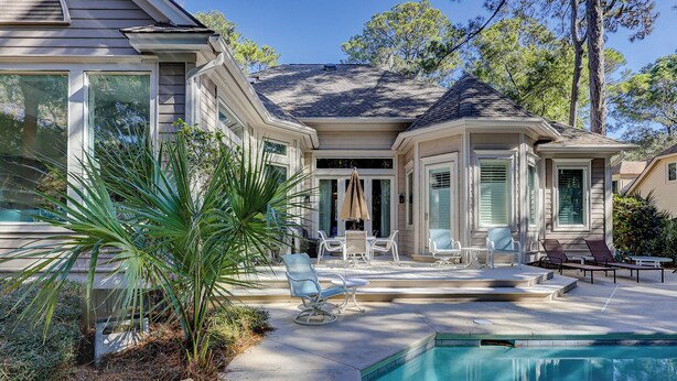 Una casa con piscina, muebles de exterior y un patio.