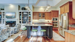 Una cocina moderna con armarios de madera, un refrigerador de acero inoxidable y una isla central con taburetes.
