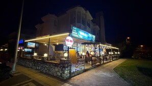 A restaurant with outdoor seating, a signboard, and a stone wall. - Rayon Apart hotel (Marmaris)