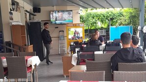 An outdoor seating area with tables and chairs, a television screen, and a vending machine. - Rayon Apart hotel (Marmaris)