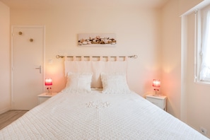 Een slaapkamer met een bed, nachtkastjes, een kunstwerk aan de muur en een raam.