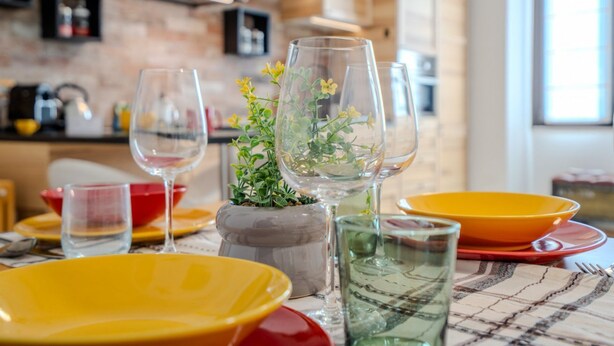 A dining table with yellow and red plates, clear glasses, and a potted plant. - GuestHost - Milanese Mountain Escape x5 (Milano)