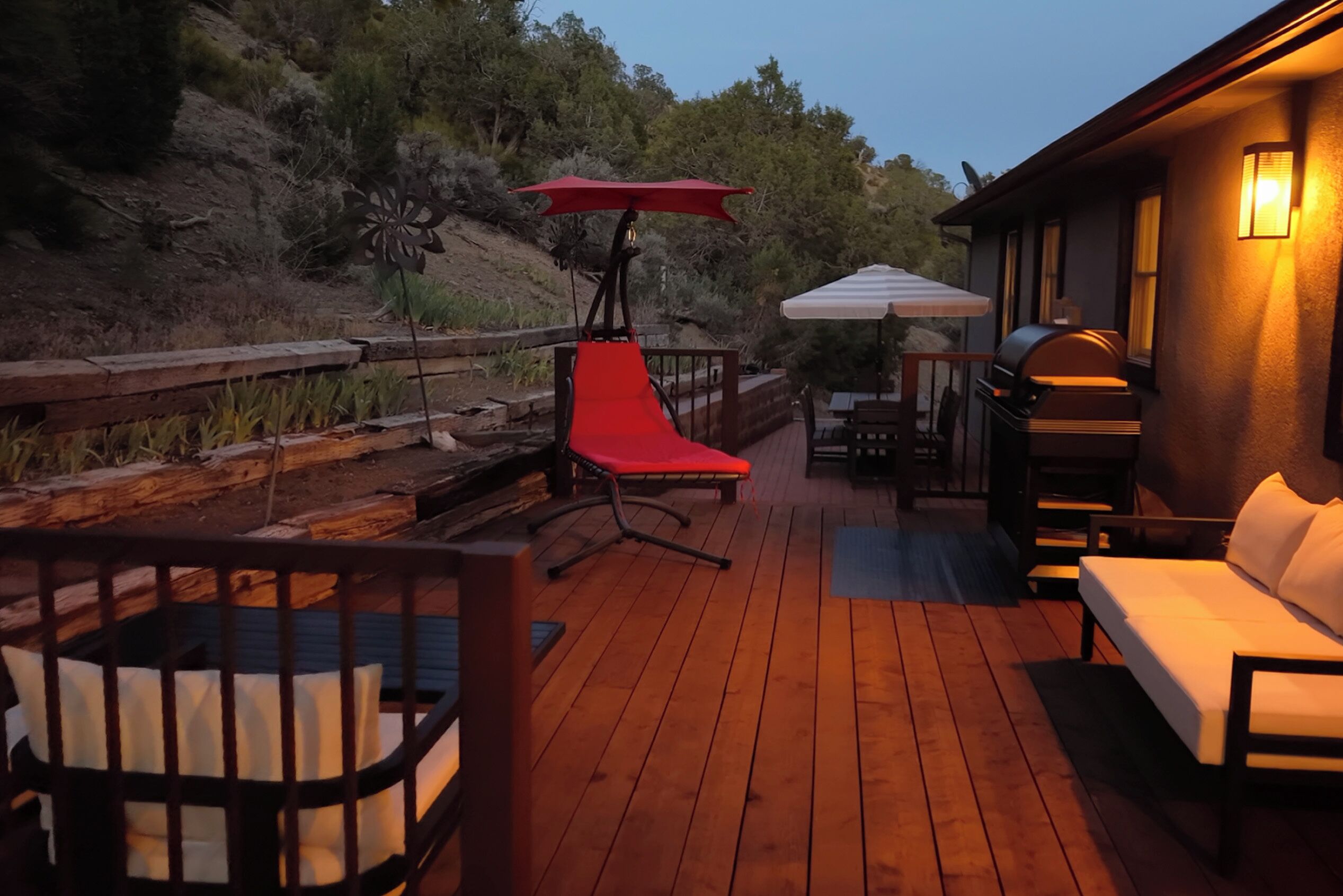 Eine Holzterrasse mit einem roten Stuhl, einem weißen Sofa und einem Grill.
