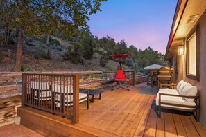 A wooden deck with outdoor furniture, a red umbrella, and a view of the surrounding landscape.