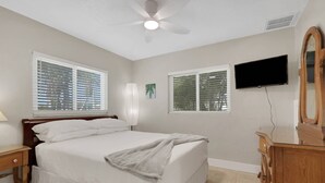 A bedroom with a bed, a nightstand, a dresser, a ceiling fan, a TV, and two windows with blinds. - 2589 Bayshore Dr (Matlacha)