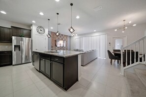 A modern kitchen with a central island, stainless steel appliances, and pendant lighting. - 5BR townhouse sleeps 13 with private pool (Kissimmee)
