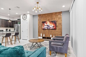 A modern living room with a television, sofa, and chairs. - 5BR townhouse sleeps 13 with private pool (Kissimmee)