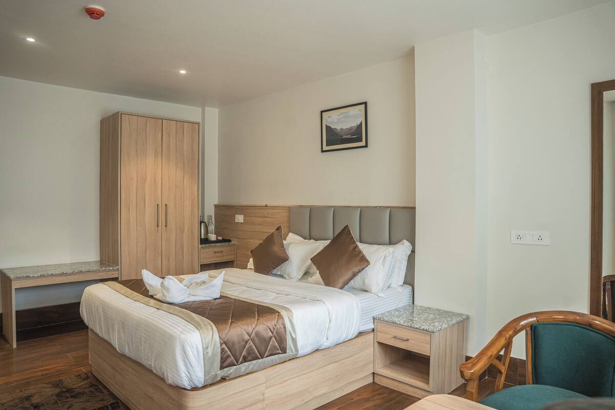 A bedroom with a bed, wooden wardrobe, bedside table, and a nightstand.