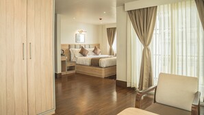 A hotel room with a wooden wardrobe, a bed with a headboard, a bedside table, and a chair. - arjay valley (Darjeeling)