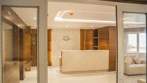 A reception area with a marble reception desk, wooden paneling, and a sofa in the background. - arjay valley (Darjeeling)