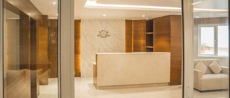 A reception area with a marble reception desk, wooden paneling, and a sofa in the background.