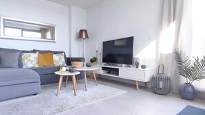 A modern living room with a grey sofa, a flat-screen TV, a coffee table, and a lamp. - Panorama Beach - Penthouse (Torrox)