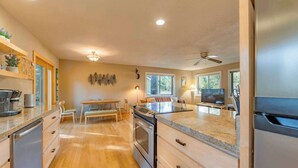 Una cocina moderna con suelo de madera, electrodomésticos de acero inoxidable y una zona de comedor con mesa y sillas.