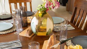 A dining table set with plates, glasses, and a vase of flowers. - Casa Verde: Grand Case Village (Grand-Case)