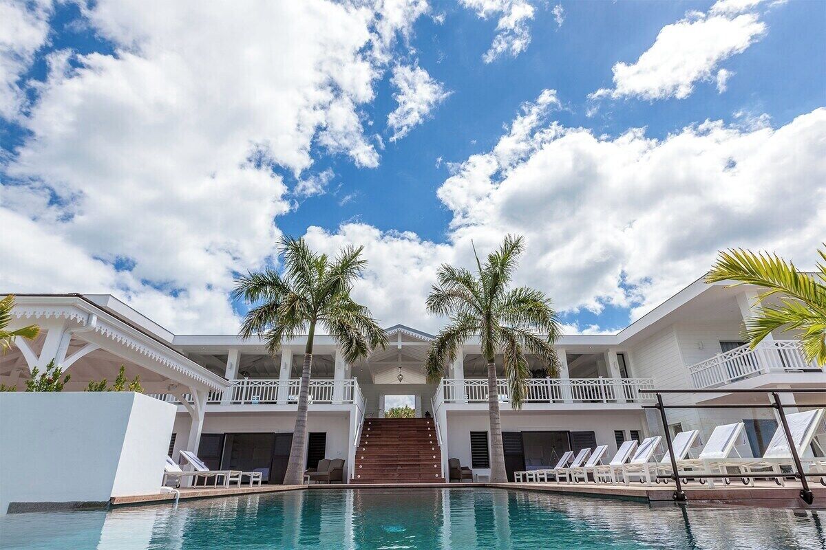 A resort with a swimming pool, palm trees, and a multi-level building with balconies.
