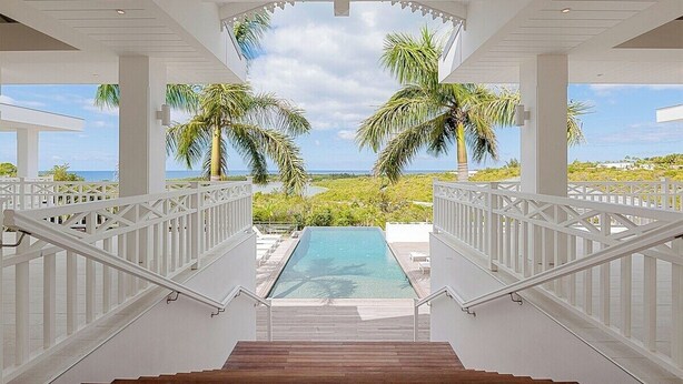 Un área de piscina con vistas a palmeras y al océano.