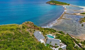 Una propiedad costera con piscina, una casa grande y vista al océano.