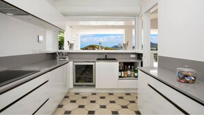 Una cocina moderna con un enfriador de vino integrado, vistas al mar y un suelo a cuadros.