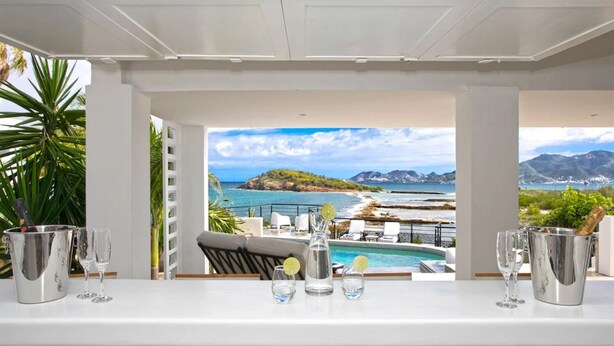 Mesa lista para comer con vistas a un paisaje costero, que incluye una playa y montañas.