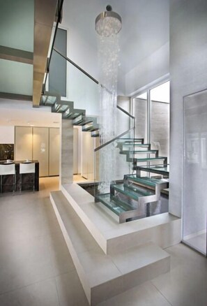 Eine moderne Treppe mit Glasgeländern und einem Wasserspiel.