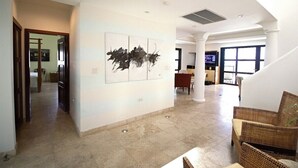A spacious living area with a high ceiling, a large window, and a modern art piece on the wall. - Bahari: Shore Pointe Community Villa (Cupecoy Beach)