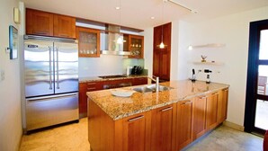 A modern kitchen with wooden cabinets, stainless steel appliances, and a granite countertop. - Bahari: Shore Pointe Community Villa (Cupecoy Beach)
