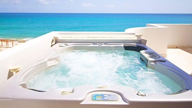 A hot tub with a control panel, surrounded by a white structure, overlooking a beach and the ocean. - Bahari: Shore Pointe Community Villa (Cupecoy Beach)