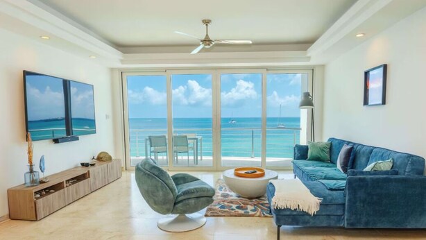 A spacious living room with a large window offering a view of the ocean. - Beach Front Condo   AMAZING PLACE TO SPEND YOUR VACATION Unit #301 (Simpson Bay)