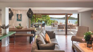 Ein geräumiger Wohnbereich mit einer großen Couch, einem Esstisch und Blick aufs Meer.
