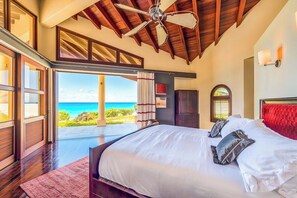 Ein Schlafzimmer mit einem großen Bett, einem Deckenventilator und Blick aufs Meer.